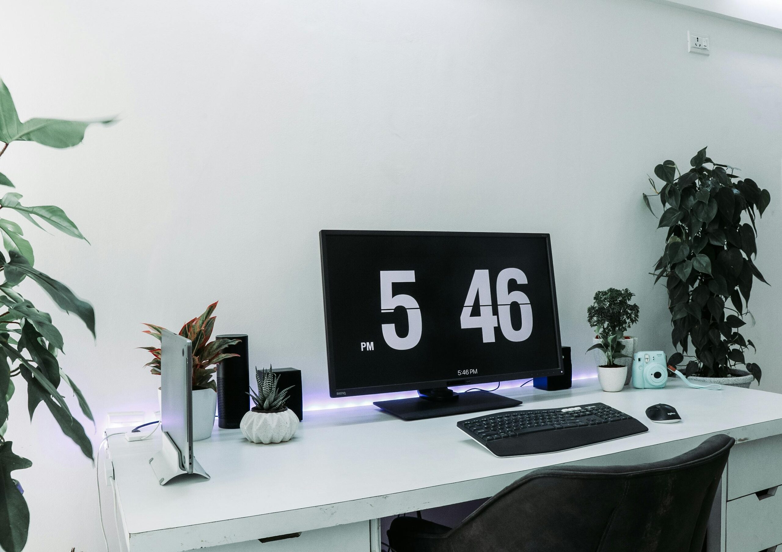 A sleek, contemporary desk setup featuring a monitor, plants, and minimalist decor for remote work.